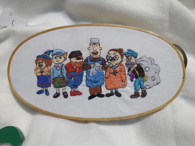 an embroidery hoop depicting characters from the professor layton game