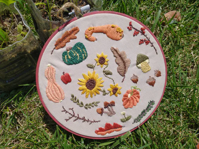 an embroidered hoop depicting gourds and fall leaves