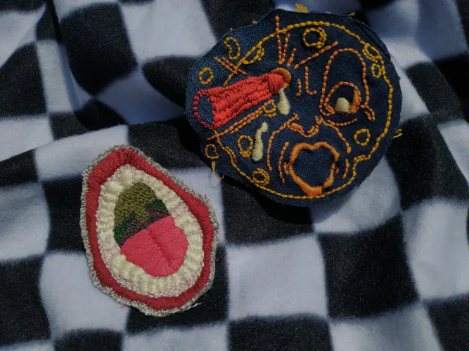 two embroidered patches depicting a moon and a mouth
